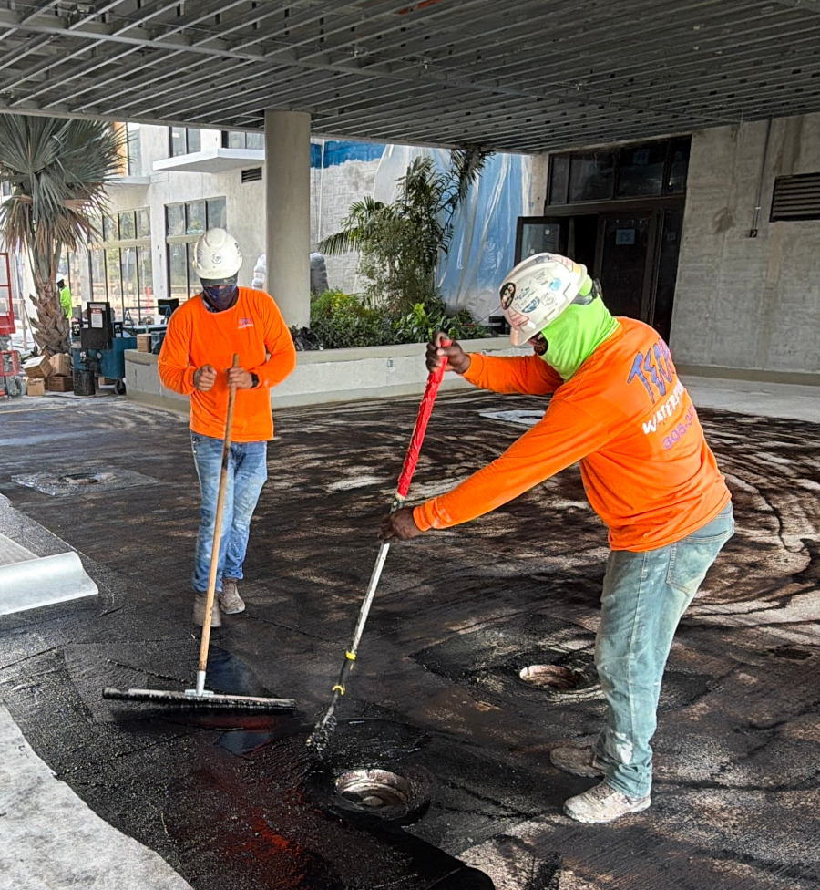 Two Tech Waterproofing crew members applying waterproofing membrane on site