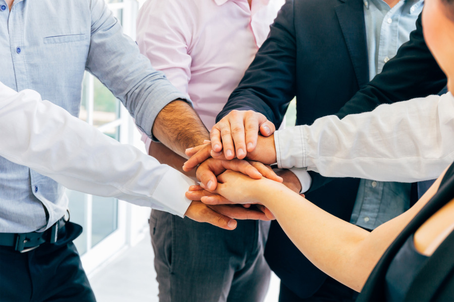 Team members joining hands to represent partnership