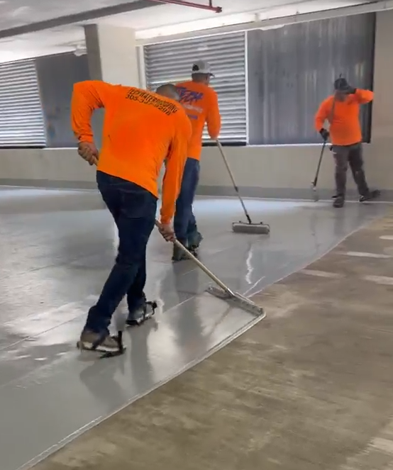 Crew applying membrane coating on a rooftop deck