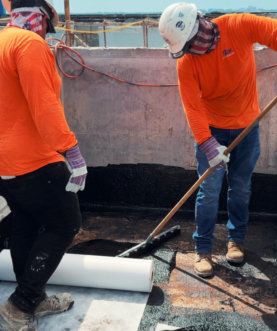 Crew applying membrane coating on a rooftop deck