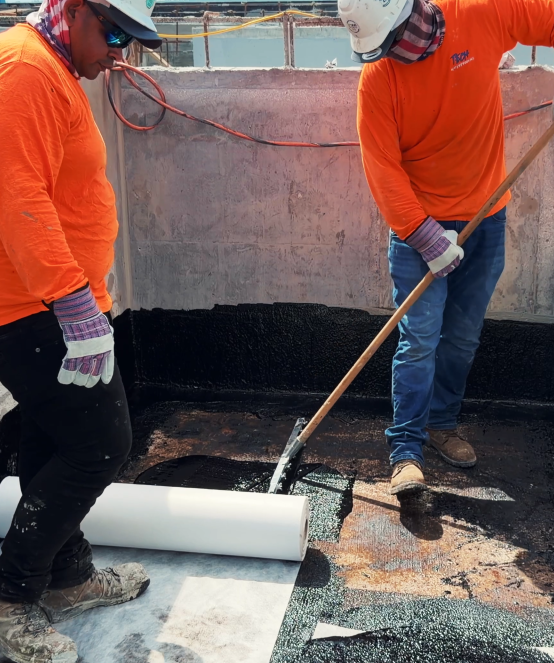 Crew applying membrane coating on a rooftop deck